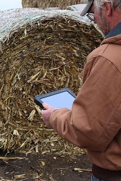 A man uses a tablet in a farm environment