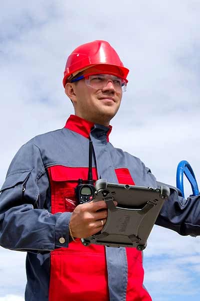 A man uses a rugged tablet in an oil field