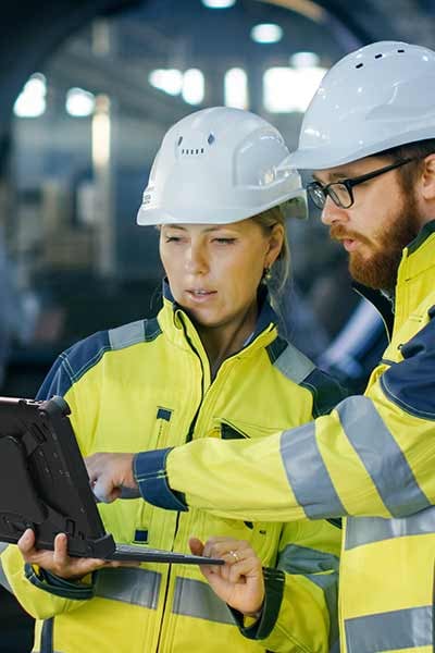 two workers use a rugged PC in a warehouse