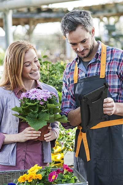 Two people look at items on a tablet in a garden center