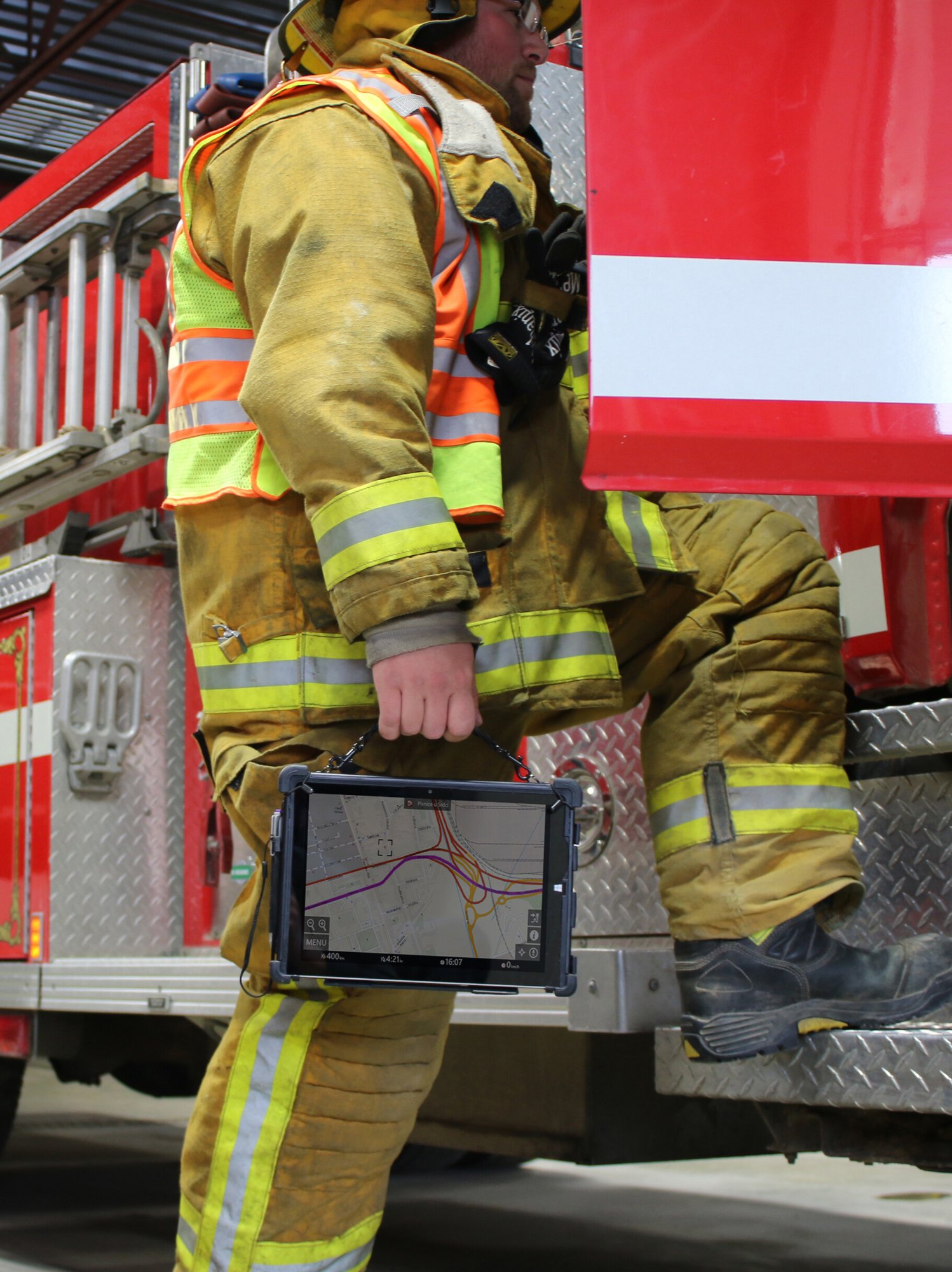 firefighter holding rugged tablet entering fire truck