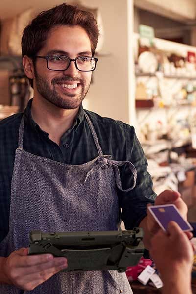 A man accepts payment in a store with a tablet