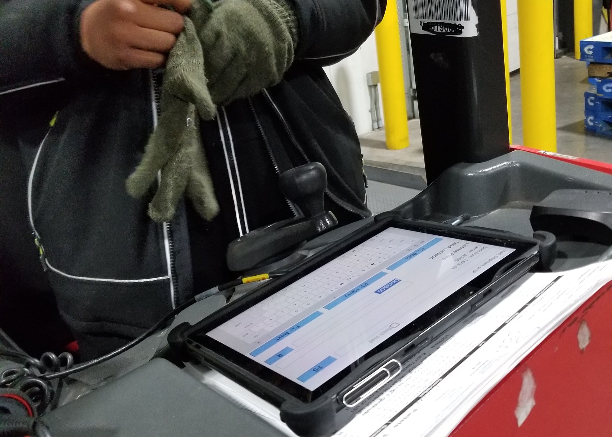 person putting on gloves next to rugged tablet