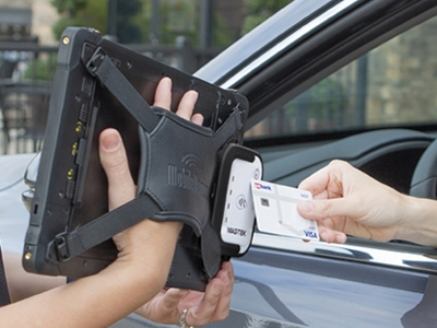 Person holding rugged tablet with integrated payment module  capturing payment from credit card