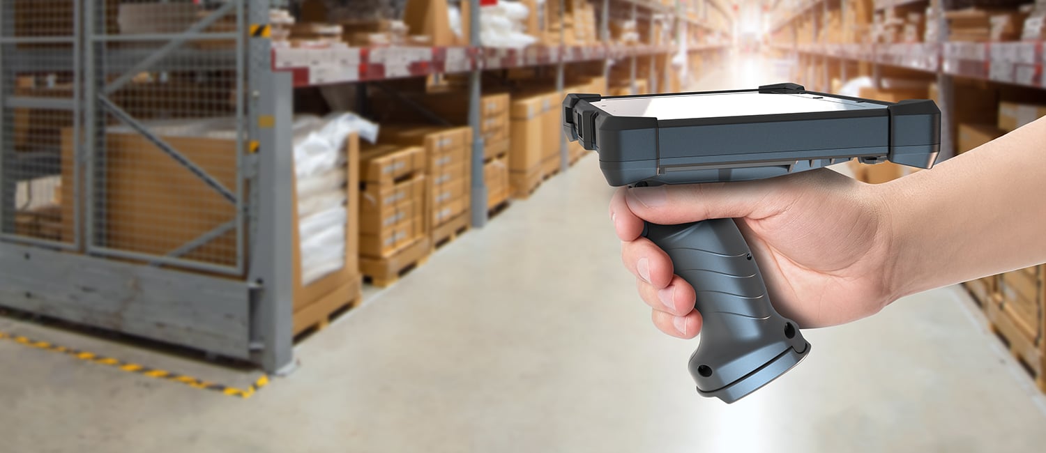 Person's hand holding scan handle with xtablet t8650 in warehouse