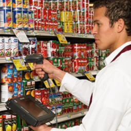 Male grocery employee holding running tablet scanning canned goods