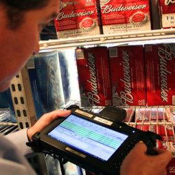 man holding rugged tablet with integrated scanner in cooler full of cases of beer