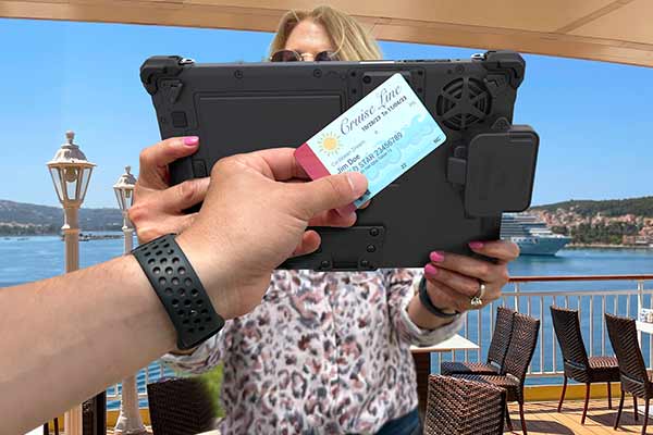 A person shows a credit card in front of a rugged tablet
