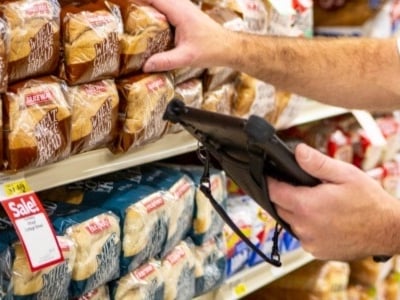 grocery clerk holding rugged tablet in bread aisle