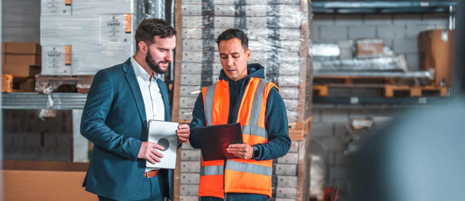 Two people discuss issues in a warehouse setting