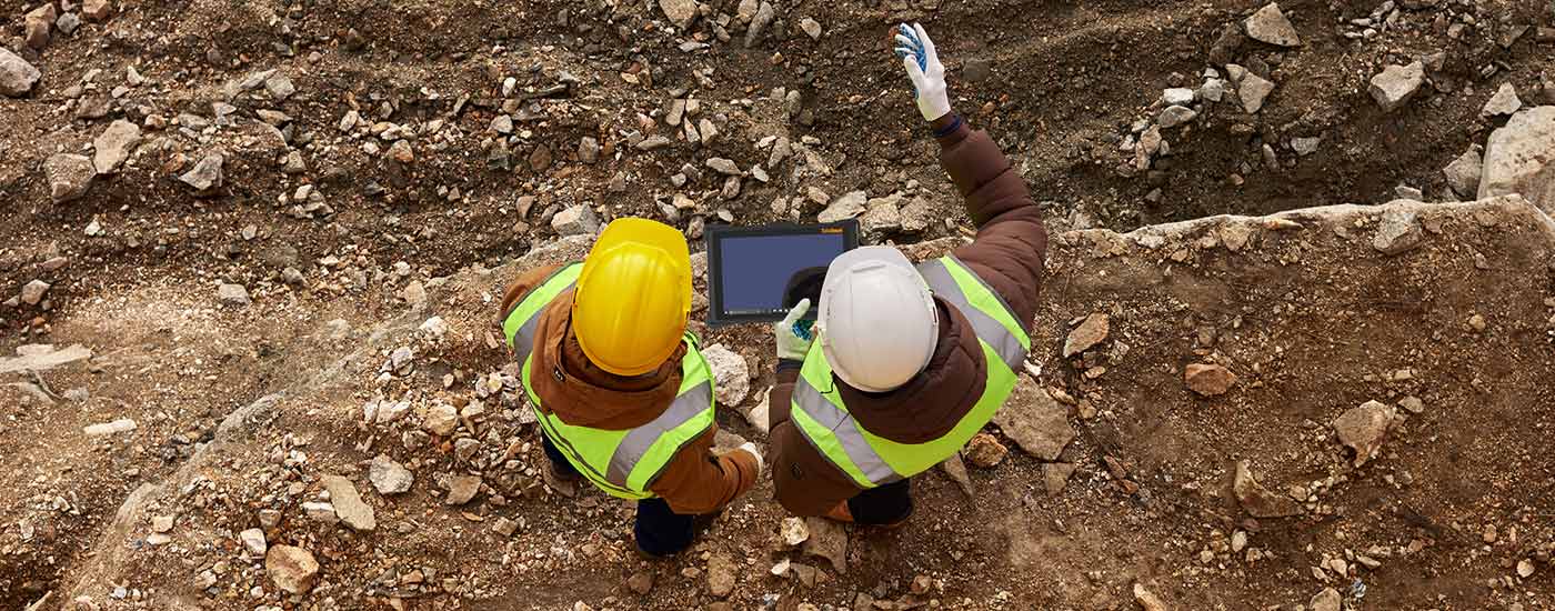 Two construction workers use a rugged tablet