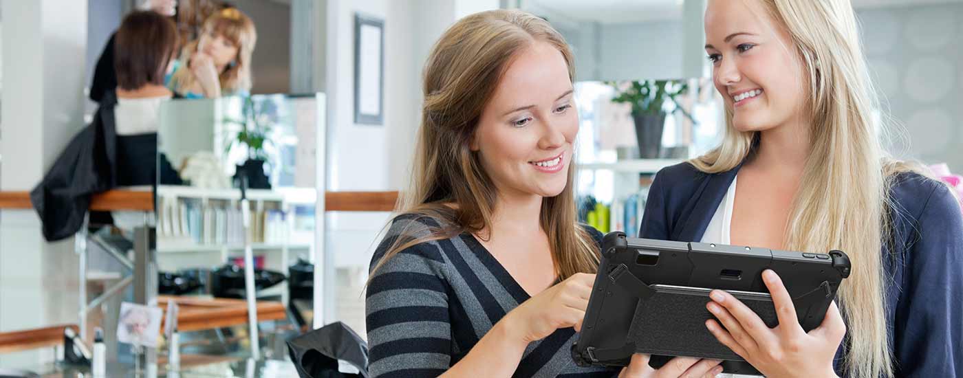 Two women use a rugged tablet in a solon setting