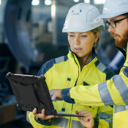 construction workers holding and looking at rugged tablet with keyboard
