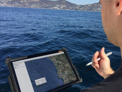 Person holding rugged tablet over ocean water