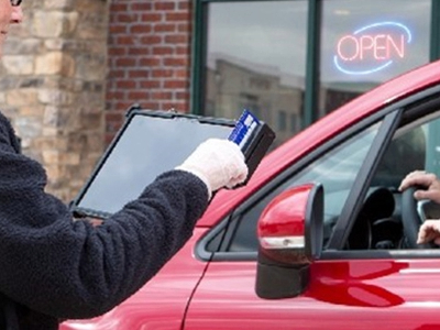 woman holding rugged tablet and swiping card in integrated payment module