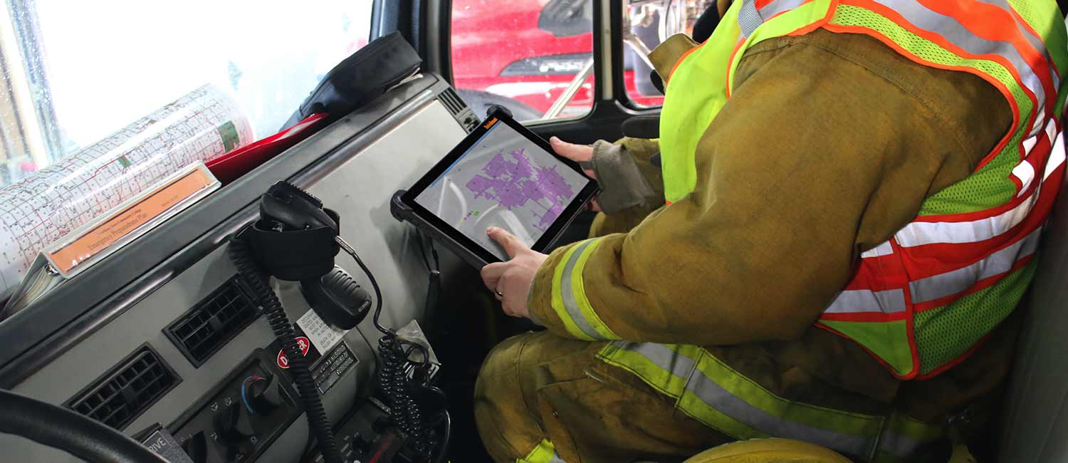 A firefighter in a truck cab with a rugged tablet