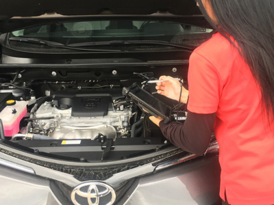 Female holding rugged tablet looking at car engine