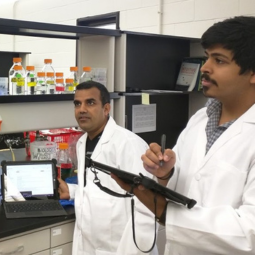 Two male holding rugged tablets in biology lab