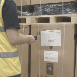 man holding rugged tablet with integrated scanner to scan barcode on cardboard box