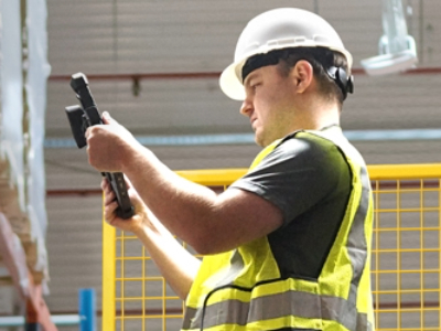 warehouse worker holding rugged tablet to dimension a pallet on an order picker