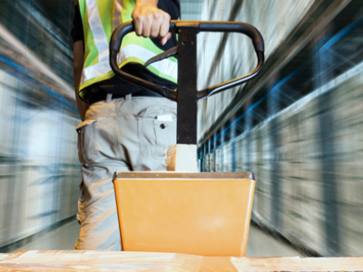 warehouse worker pulling pallet with boxes on top